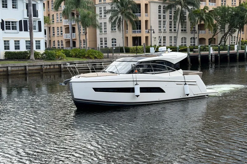 The Image of 2019 Carver C34 yacht cruising near waterfront buildings and palm trees. - 0