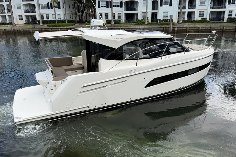 Slide: The Image of 2019 Carver C34 yacht cruising on a calm waterway near residential buildings. - 2