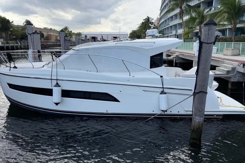 Slide: The Image of 2019 Carver C34 yacht docked at marina, sleek design, calm water, overcast sky. - 26