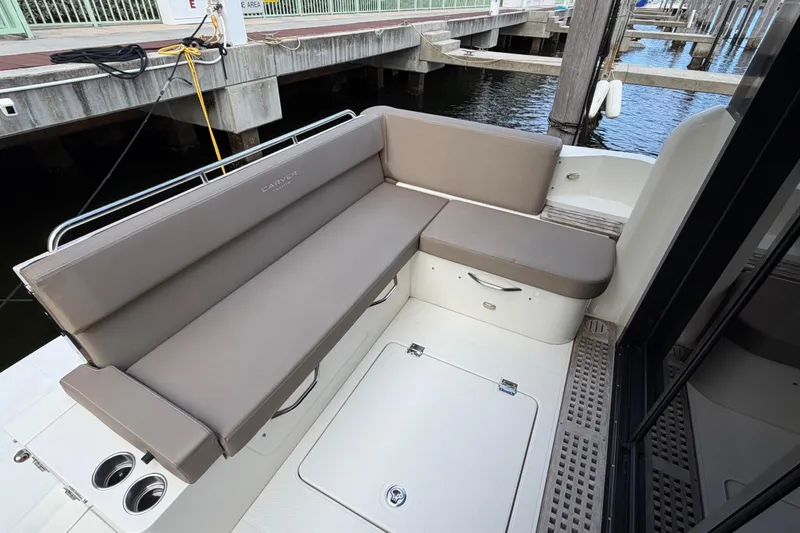 Slide: The Image of 2019 Carver C34 yacht seating area with beige cushions at a marina dock. - 28