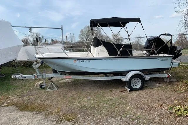 Slide: The Image of 2023 Boston Whaler 170 Montauk boat on trailer, parked outdoors with canopy. - 2