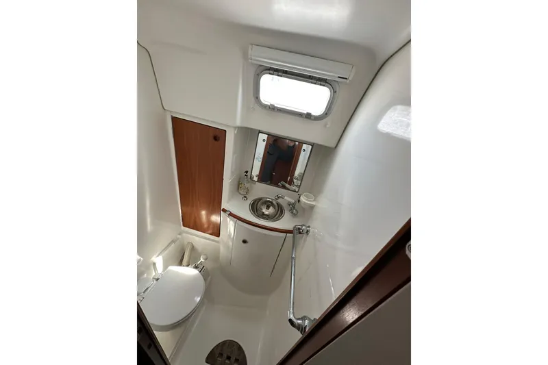 Slide: The Image of Bathroom interior of a 2000 Beneteau 50 yacht, featuring sink, toilet, and porthole. - 104