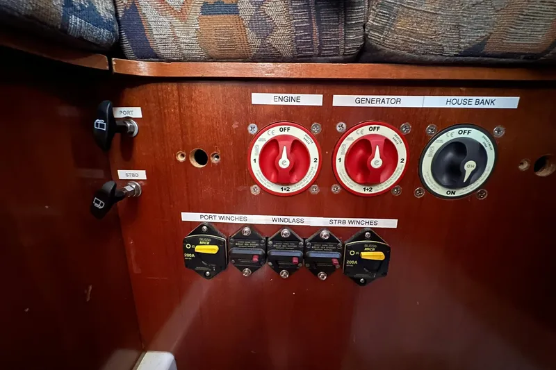 Slide: The Image of Control panel of a 2000 Beneteau 50 yacht, featuring engine, generator, and house bank switches. - 105