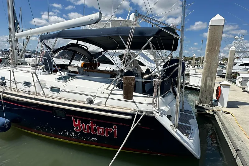 Slide: The Image of Beneteau 50 sailboat docked at marina, 2000 model, with blue canopy and clear skies. - 3