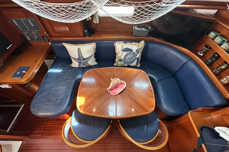Slide: The Image of Interior of 2000 Beneteau 50 yacht with blue seating and wooden table. - 77