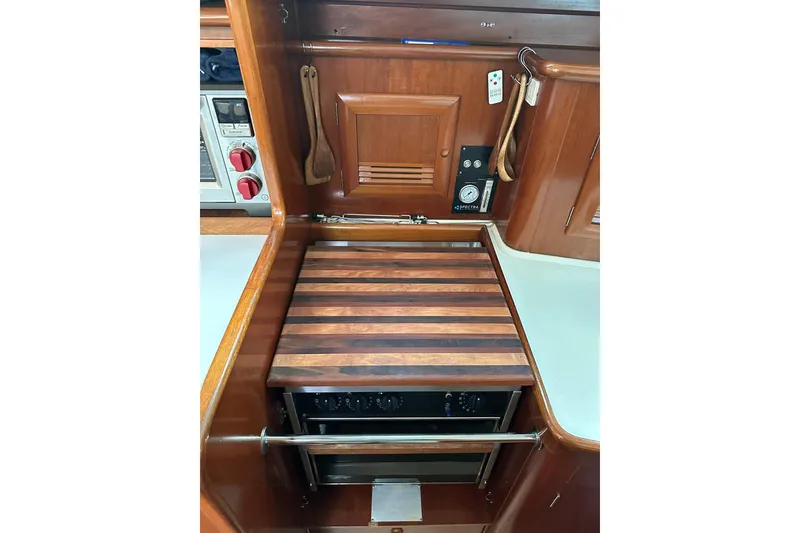 Slide: The Image of Galley kitchen in 2000 Beneteau 50 yacht with wooden cabinetry and stove. - 84