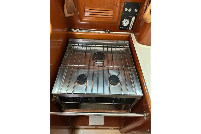 Slide: The Image of Galley stove in 2000 Beneteau 50 yacht, featuring three burners and wooden cabinetry. - 86