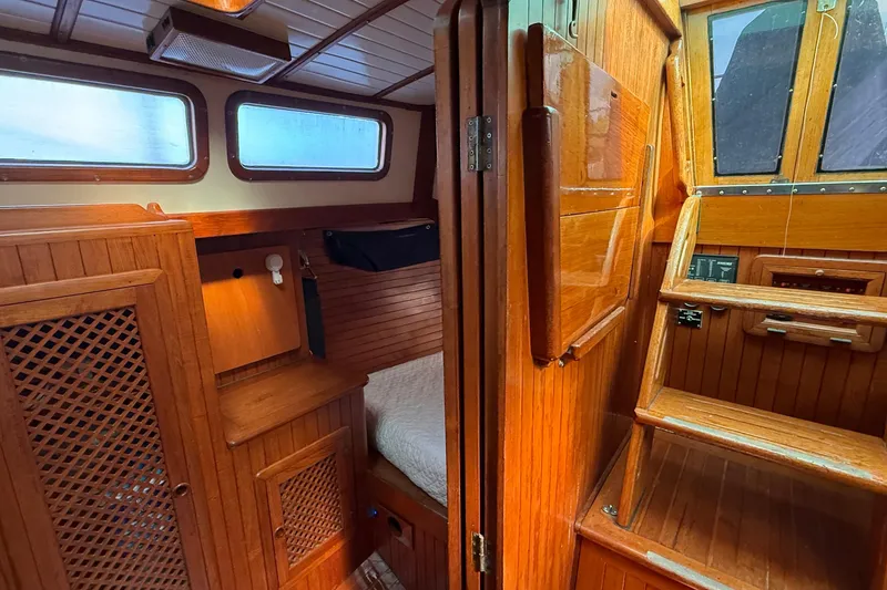 Slide: The Image of Interior of a 1986 Westwind 38 sailboat, featuring wooden cabinetry and cozy sleeping area. - 19
