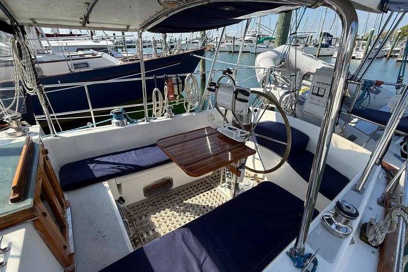 Slide: The Image of Cockpit of 1986 Westwind 38 sailboat with seating, steering wheel, and marina view. - 7
