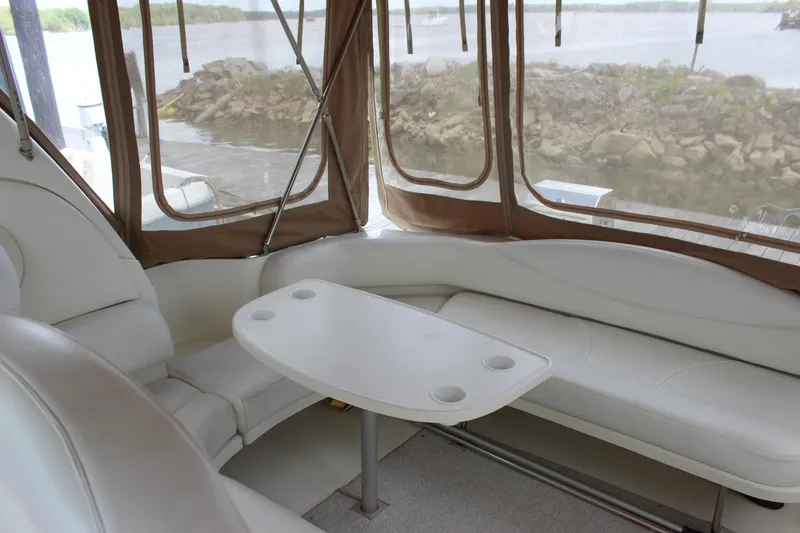 Slide: The Image of Interior of 2001 Sea Ray 380 Sundancer with white seating and table, overlooking water. - 8