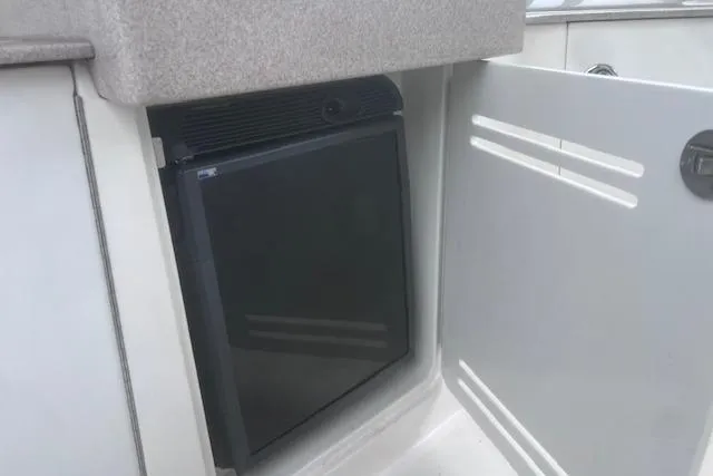 Slide: The Image of 2007 Sea Ray Sundancer 310 mini fridge in open cabinet, showcasing compact storage. - 21