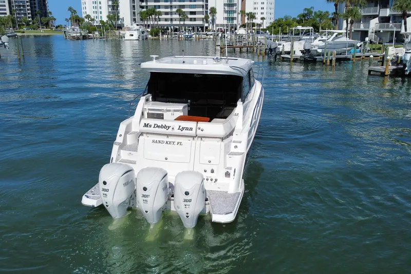 Slide: The Image of 2022 Regal 38 XO yacht with triple Yamaha engines in a marina setting. - 2