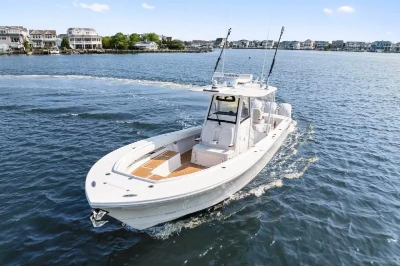 The Image of 2024 Regulator 34 boat cruising on a scenic waterfront with houses in the background. - 0