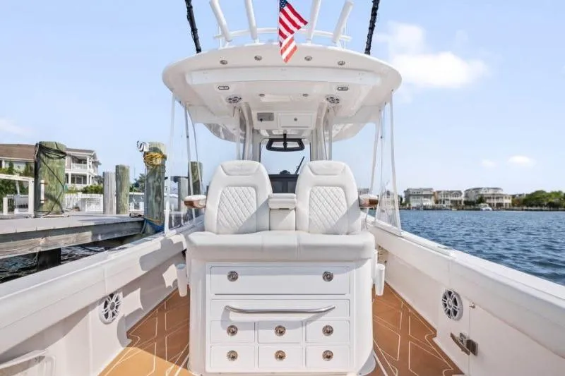 Slide: The Image of 2024 Regulator 34 boat interior with luxury seating and American flag, dockside view. - 9