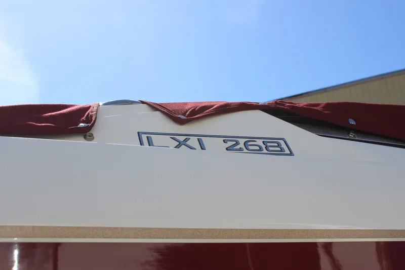 Slide: The Image of 2005 Larson LXi 268 boat with maroon cover under clear blue sky. - 17