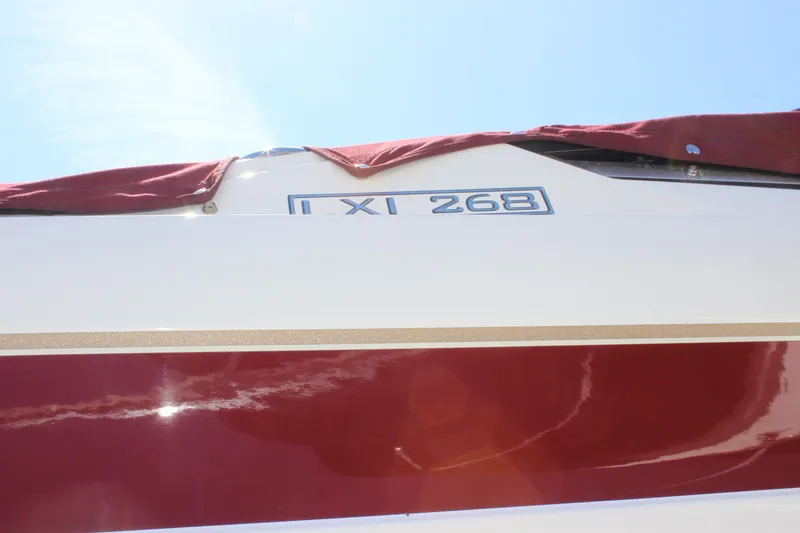 Slide: The Image of 2005 Larson LXi 268 boat with red cover and clear sky background. - 18