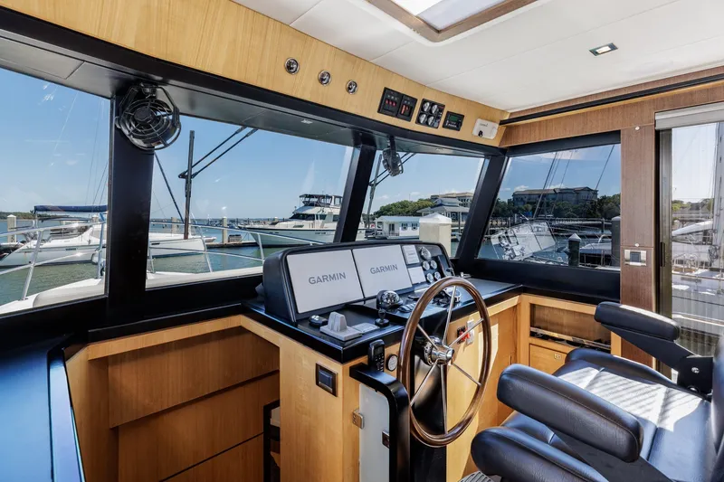 Slide: The Image of 2023 North Pacific 49 Euro yacht helm with Garmin navigation, luxurious interior, and marina view. - 10