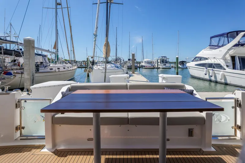 Slide: The Image of 2023 North Pacific 49 Euro yacht with marina view, featuring a wooden table and seating area. - 25