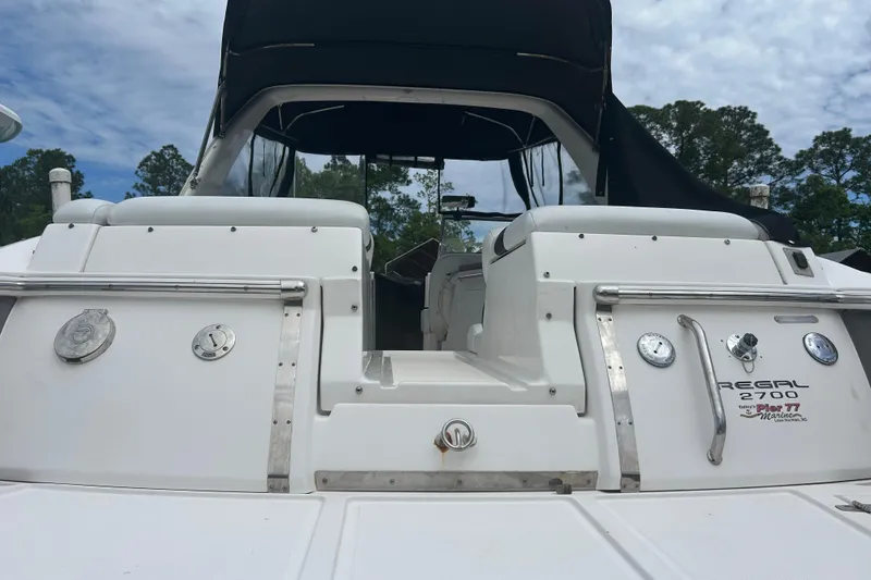 Slide: The Image of 2008 Regal 2700 Bowrider boat with white exterior and black canopy, docked outdoors. - 10