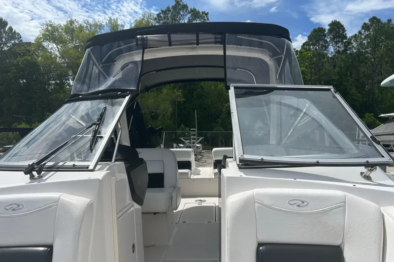 Slide: The Image of 2008 Regal 2700 Bowrider boat with open cockpit and windshield, surrounded by trees. - 12