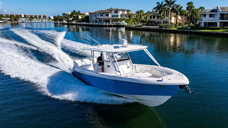 Slide: The Image of 2019 Everglades 355 Center Console cruising on calm water near coastal homes. - 9