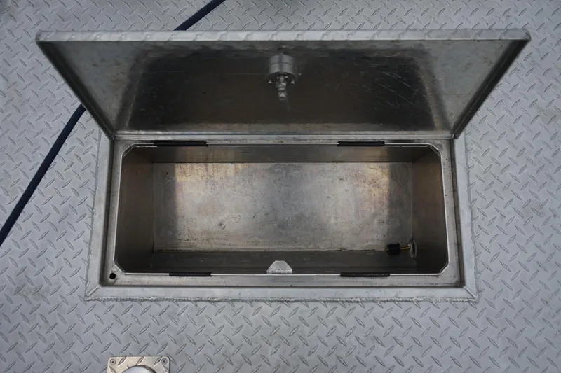 Slide: The Image of Open storage compartment on 2021 Wooldridge 16 Alaskan LT boat, featuring diamond plate flooring. - 13