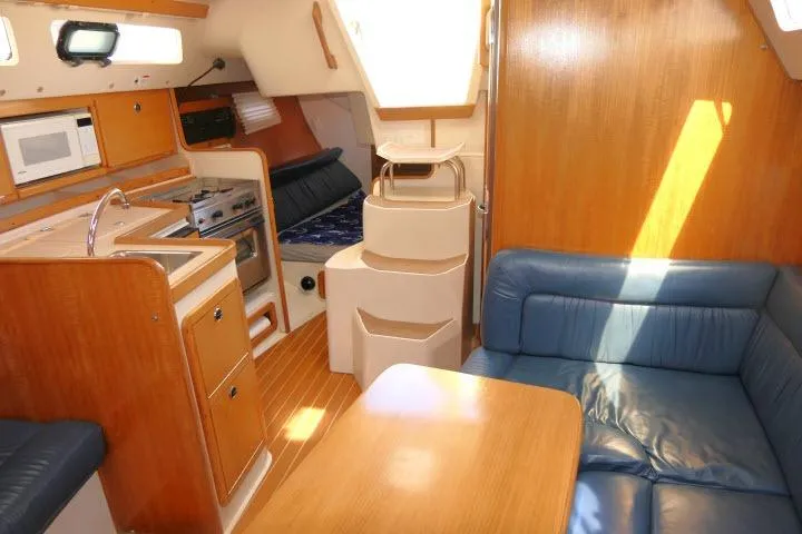 Slide: The Image of Interior of 2001 Catalina 310 sailboat with kitchen, seating, and wooden finishes. - 10