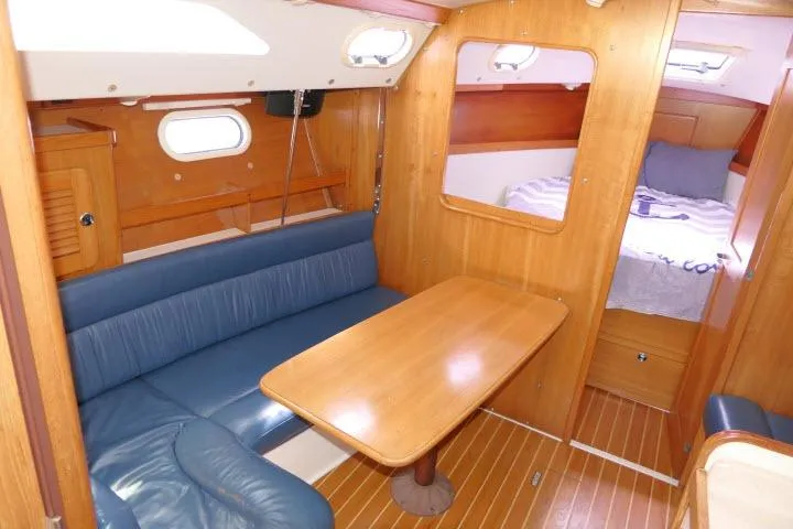 Slide: The Image of Interior of a 2001 Catalina 310 sailboat with wooden furnishings and blue seating. - 2