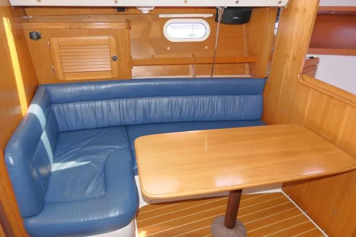 Slide: The Image of Interior of 2001 Catalina 310 sailboat with blue seating and wooden table. - 3
