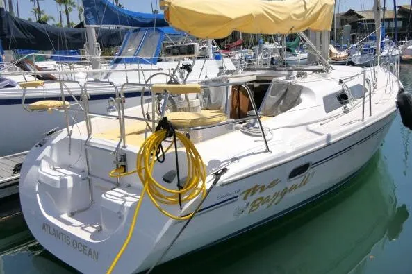 Slide: The Image of 2001 Catalina 310 sailboat docked, featuring yellow canopy and coiled rope on deck. - 46
