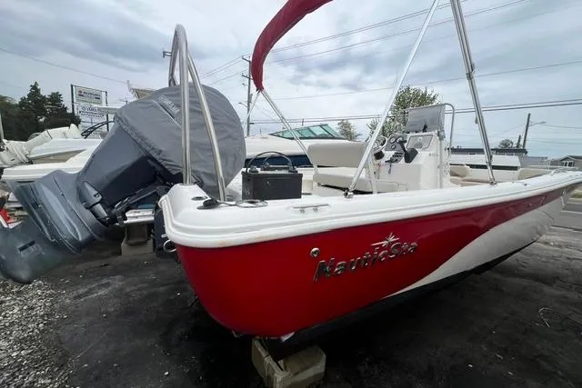 Slide: The Image of 2013 NauticStar 210 Coastal boat with red hull and outboard motor. - 3