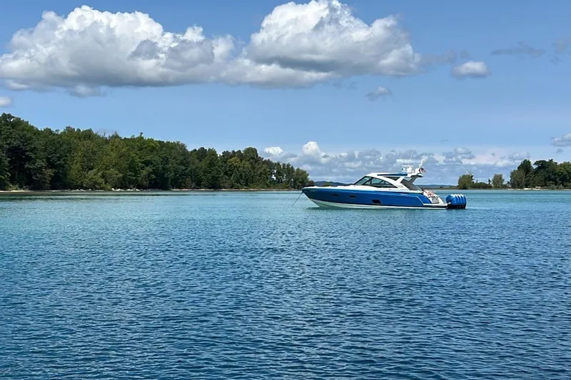 Slide: The Image of A 2019 Formula 430 Super Sport Crossover boat on a serene lake with lush green shoreline. - 2