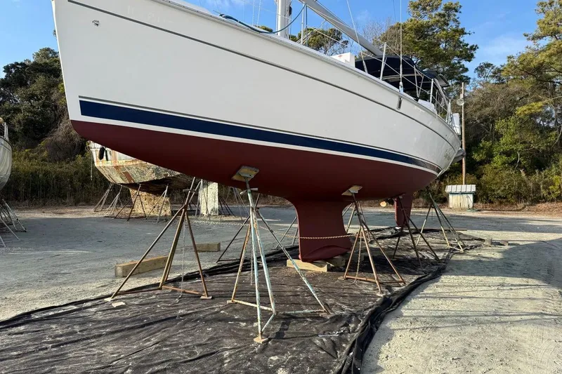 Slide: The Image of 2009 Hunter 38 sailboat on stands, white hull, red bottom, outdoor setting. - 11