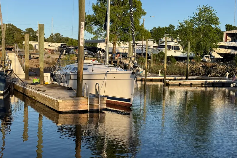 Slide: The Image of 2009 Hunter 38 sailboat docked at a marina, surrounded by calm water and greenery. - 6