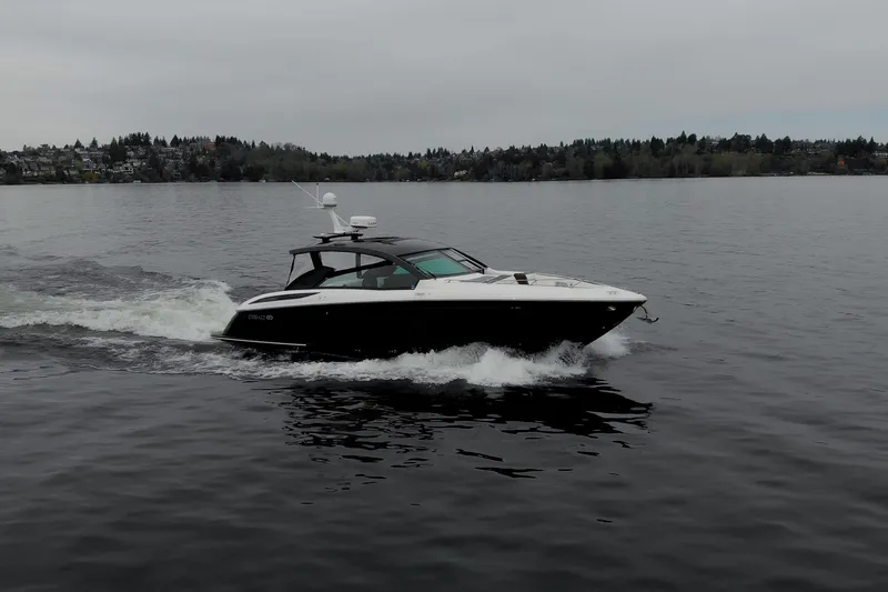 Slide: The Image of 2019 Cobalt A36 boat cruising on a calm lake with distant shoreline. - 2