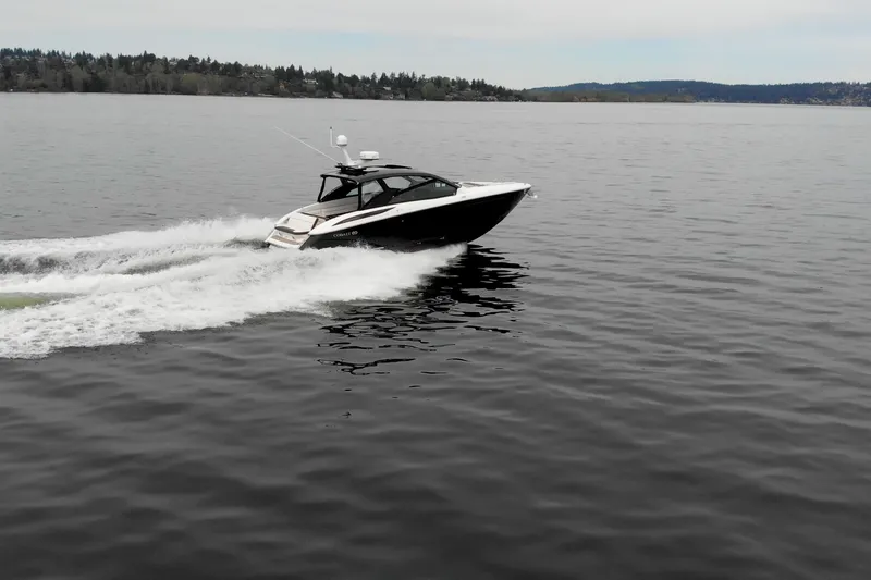 Slide: The Image of 2019 Cobalt A36 boat cruising on a calm lake with scenic background. - 3