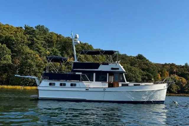 The Image of 1983 Grand Banks 42 Motoryacht on calm water, surrounded by lush greenery. - 0