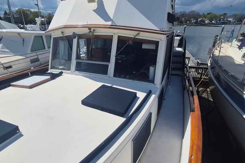 Slide: The Image of 1983 Grand Banks 42 Motoryacht with polished wooden railings in a marina setting. - 32