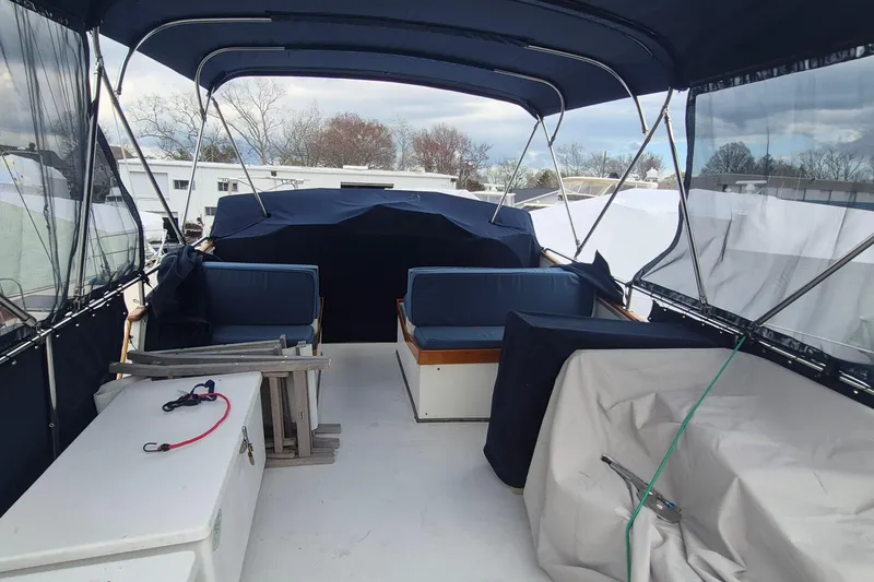 Slide: The Image of 1983 Grand Banks 42 Motoryacht deck with blue cushioned seating and protective covers. - 51
