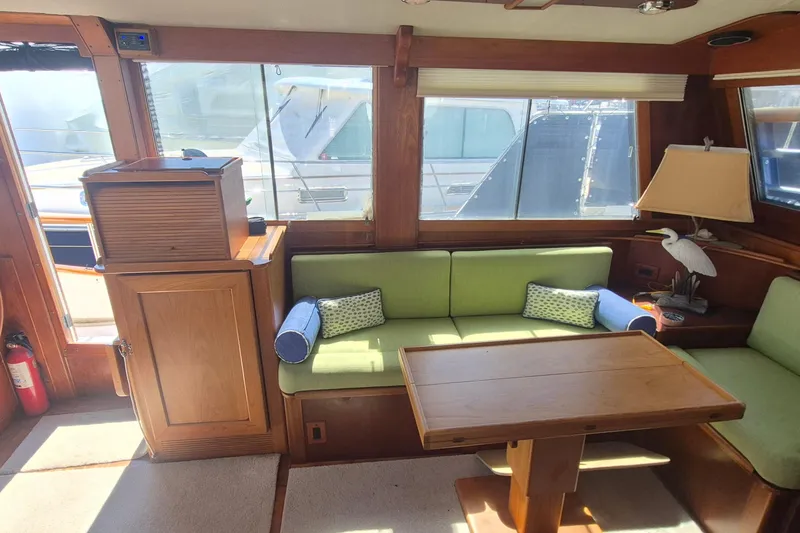 Slide: The Image of Interior of 1983 Grand Banks 42 Motoryacht with green seating and wooden table. - 7