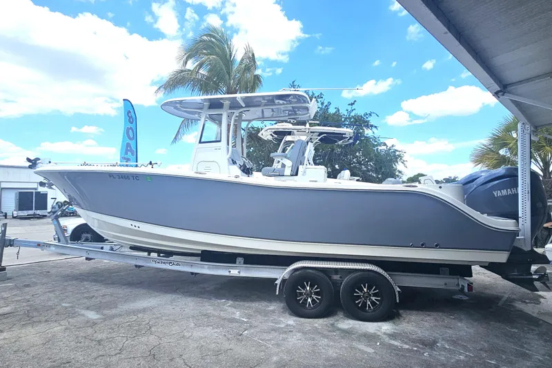 Slide: The Image of 2022 NauticStar 28 XS boat on trailer, parked outdoors under a clear blue sky. - 3