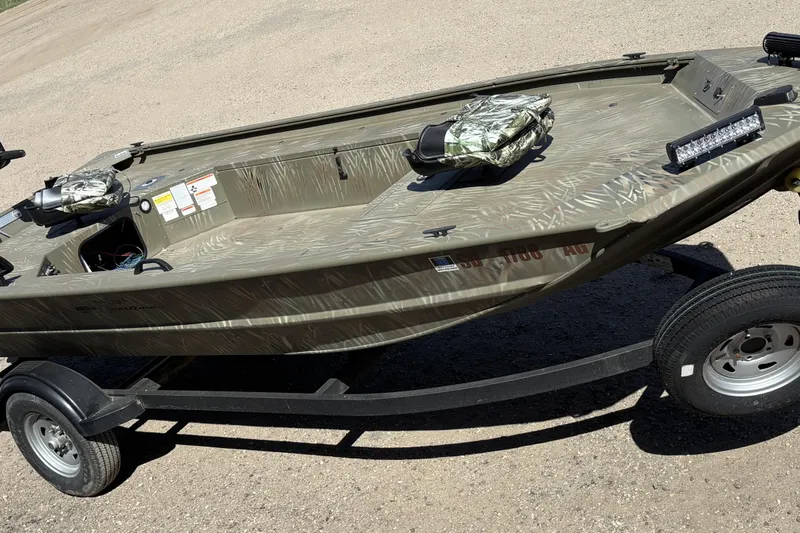 Slide: The Image of 2024 Tracker Grizzly 1654 T Sportsman boat on trailer, camo design, outdoor setting. - 7