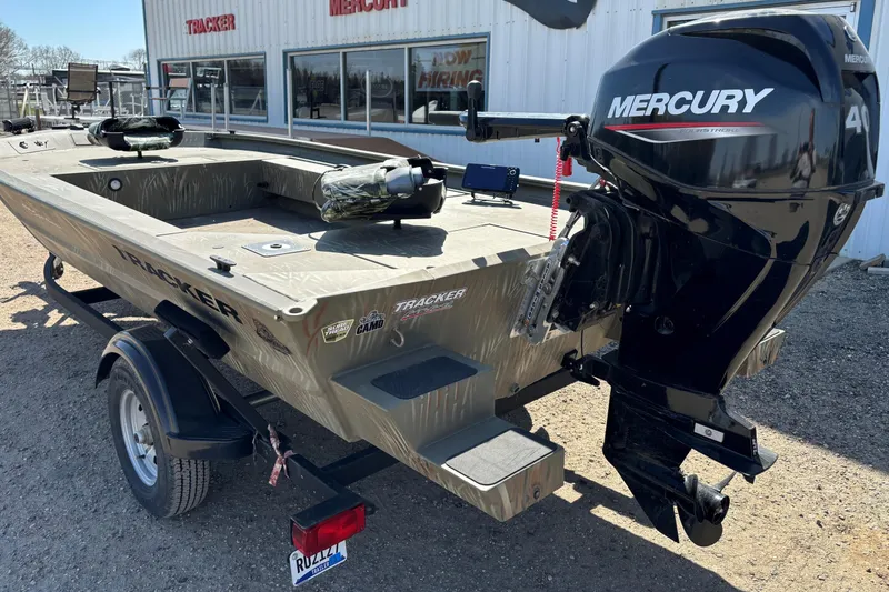 Slide: The Image of 2024 Tracker Grizzly 1654 T Sportsman boat with Mercury outboard motor, parked outdoors. - 8