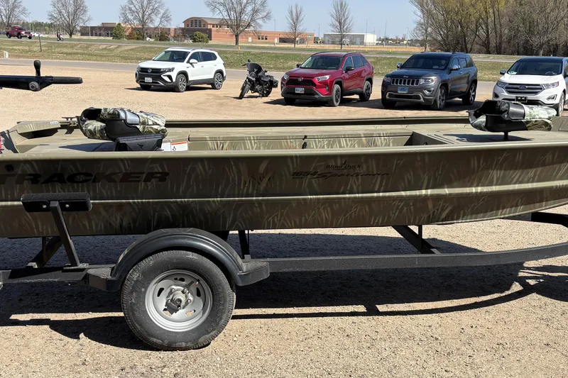 Slide: The Image of 2024 Tracker Grizzly 1654 T Sportsman boat on trailer, parked in lot with cars. - 9