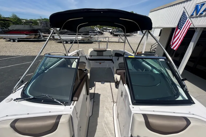 Slide: The Image of 2018 Chaparral 267 SSX boat with canopy, docked near showroom and American flag. - 18