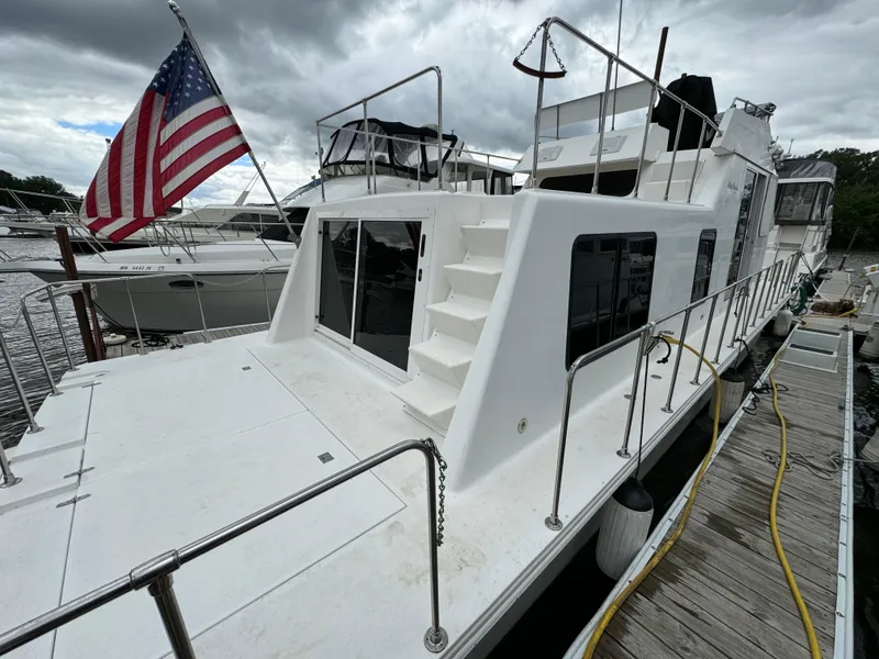 The Image of 2008 Holiday Mansion 37 houseboat docked, featuring an American flag and spacious deck. - 0