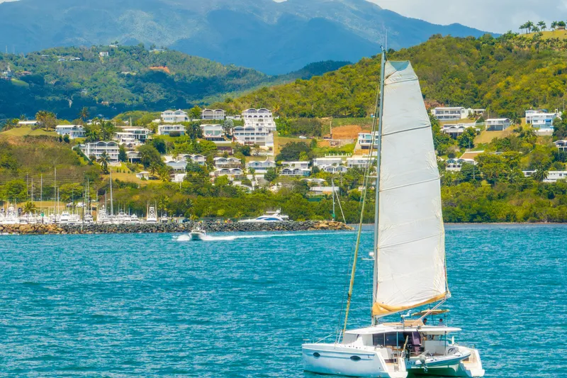 Slide: The Image of Sailing catamaran Fountaine Pajot Helia 44, 2014, on turquoise waters near lush hillside. - 0