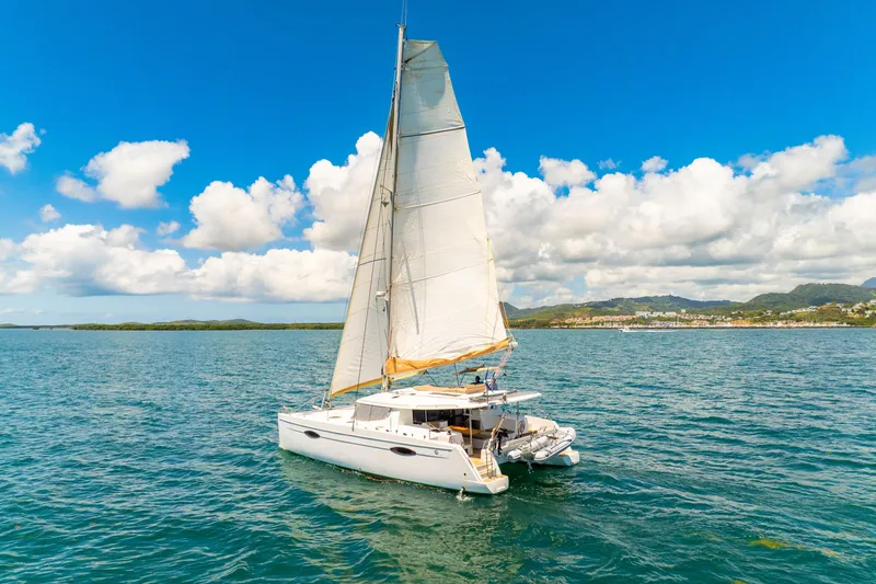 Slide: The Image of 2014 Fountaine Pajot Helia 44 catamaran sailing on a sunny day with scenic coastline. - 52