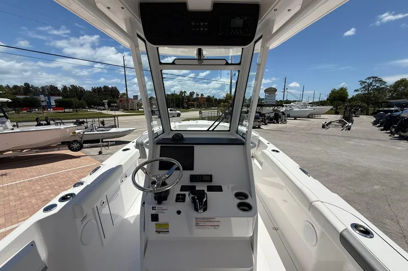 Slide: The Image of 2026 Edgewater 250CC boat cockpit with steering wheel and controls, parked outdoors. - 10