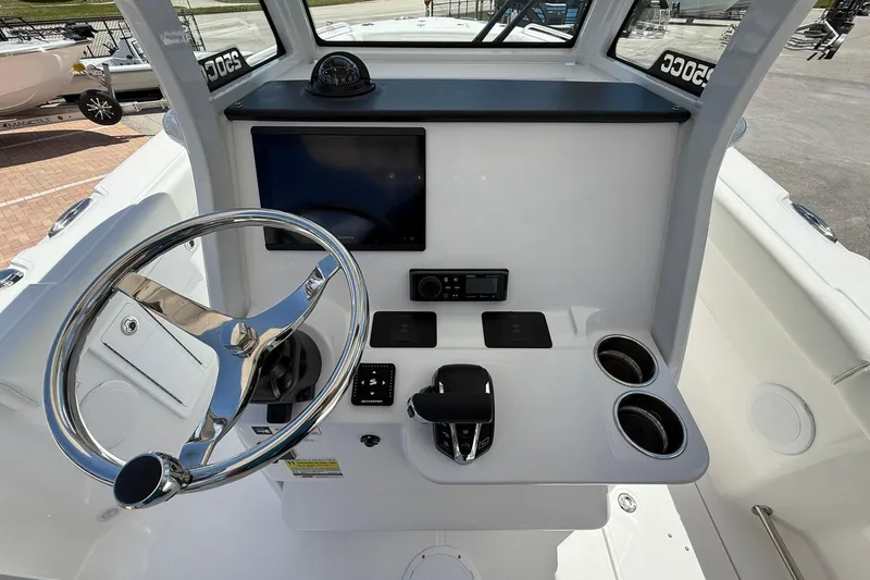 Slide: The Image of 2026 Edgewater 250CC boat helm with steering wheel, controls, and cup holders. - 12